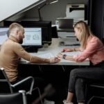 Two architects discuss plans in a contemporary office, focusing on project details.