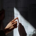 A detailed examination of construction blueprints under dramatic lighting.